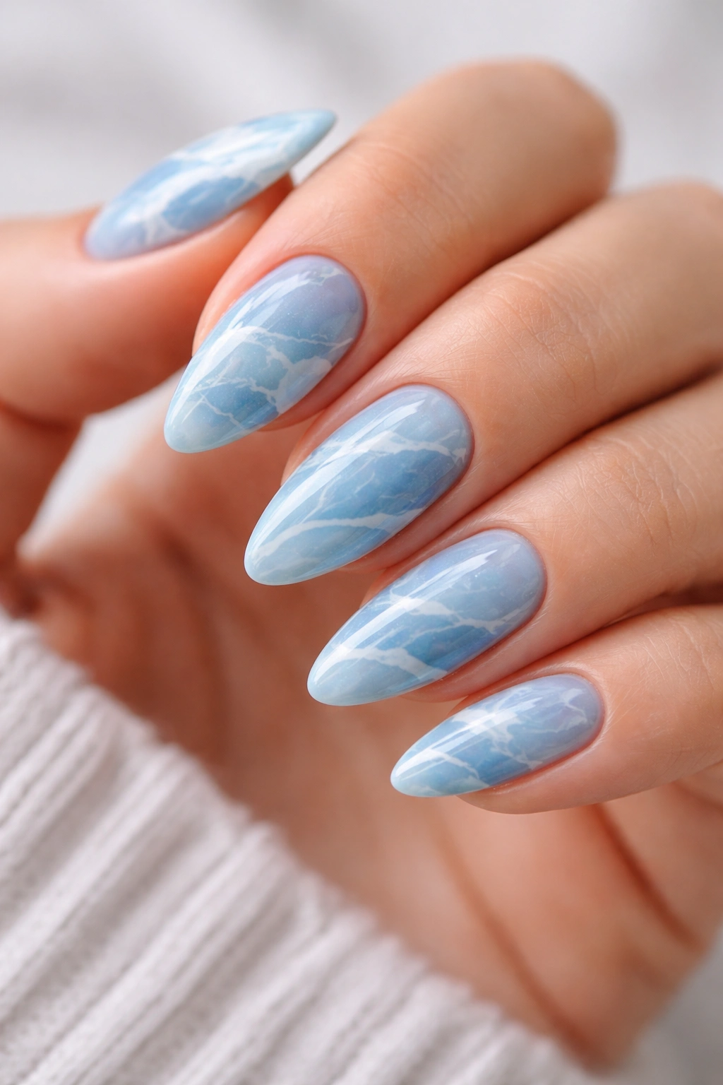 Close-up of blue marble almond nails with white veining