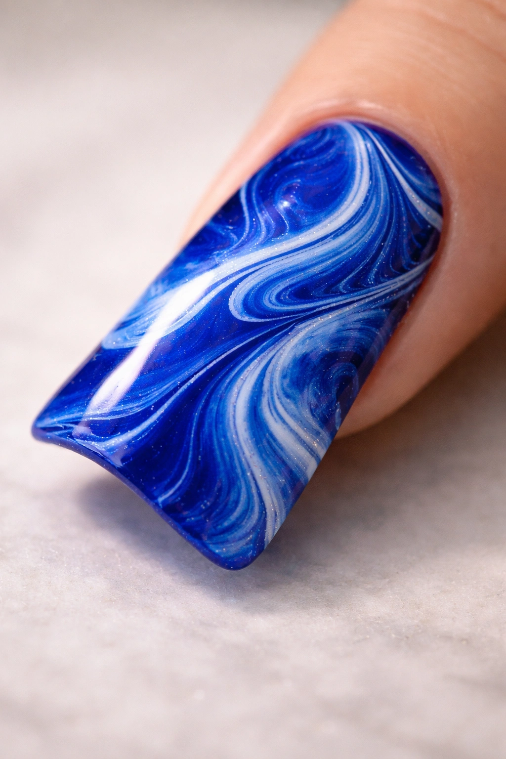 Duck nail with royal blue marbled finish and white swirls