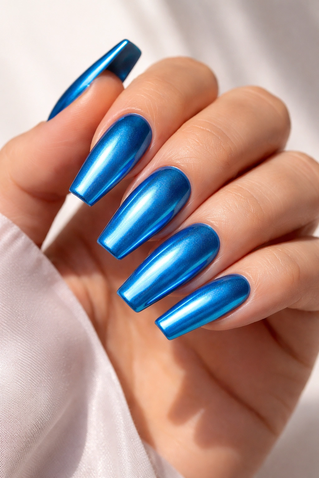 Close-up of a hand with medium coffin nails bright blue metallic polish