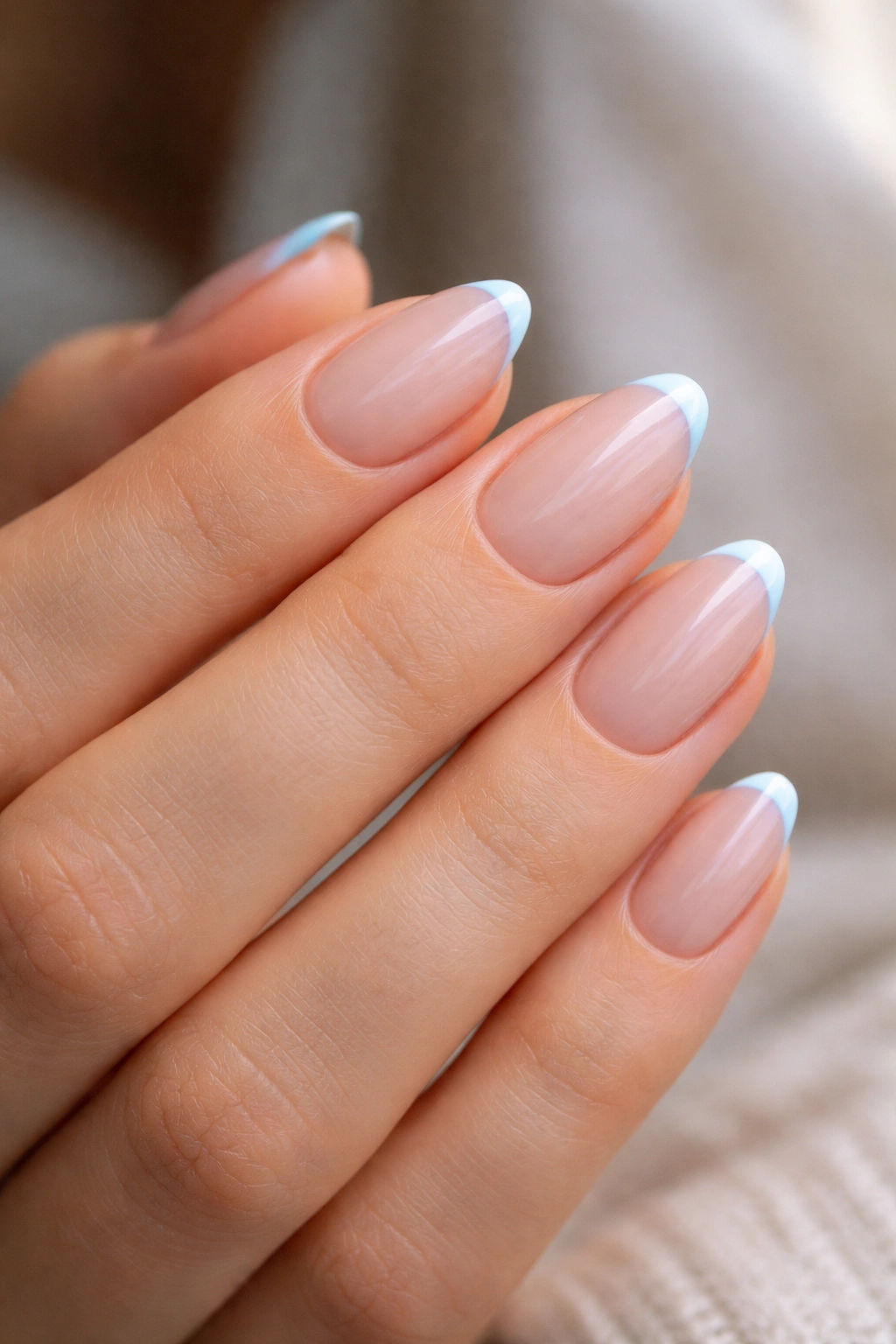Close-up of short almond nails with blue micro French tips