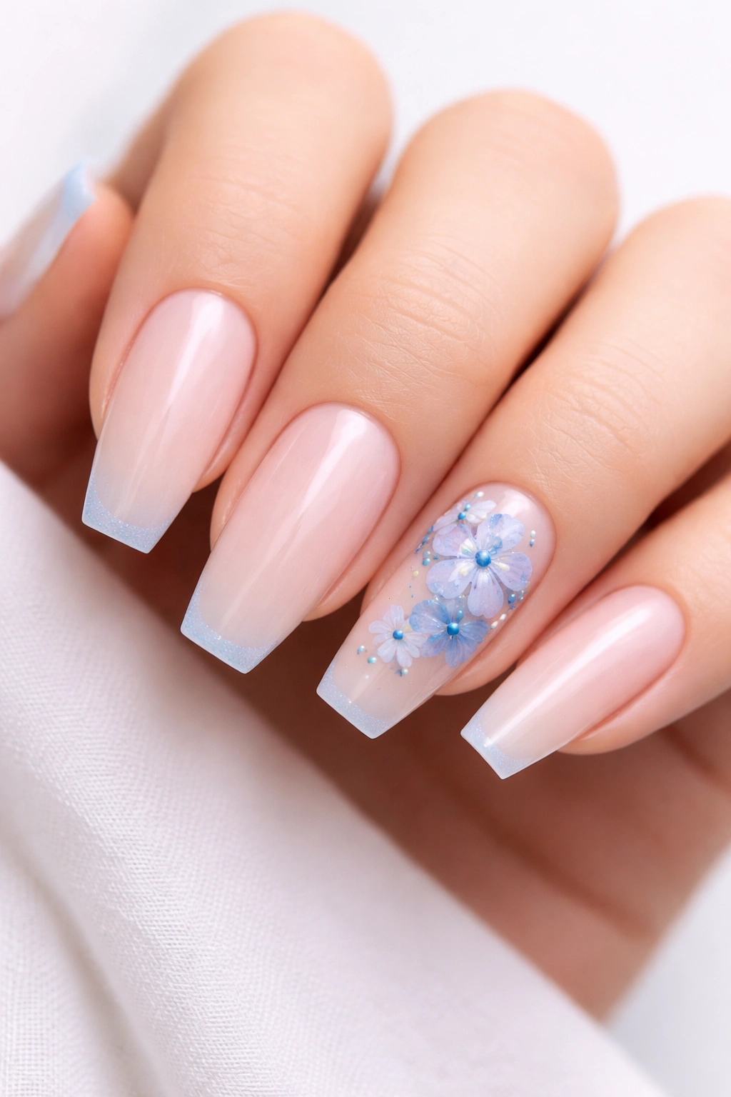 Close-up of blue floral accent nails on a sheer base with two accented nails featuring tiny airy flowers