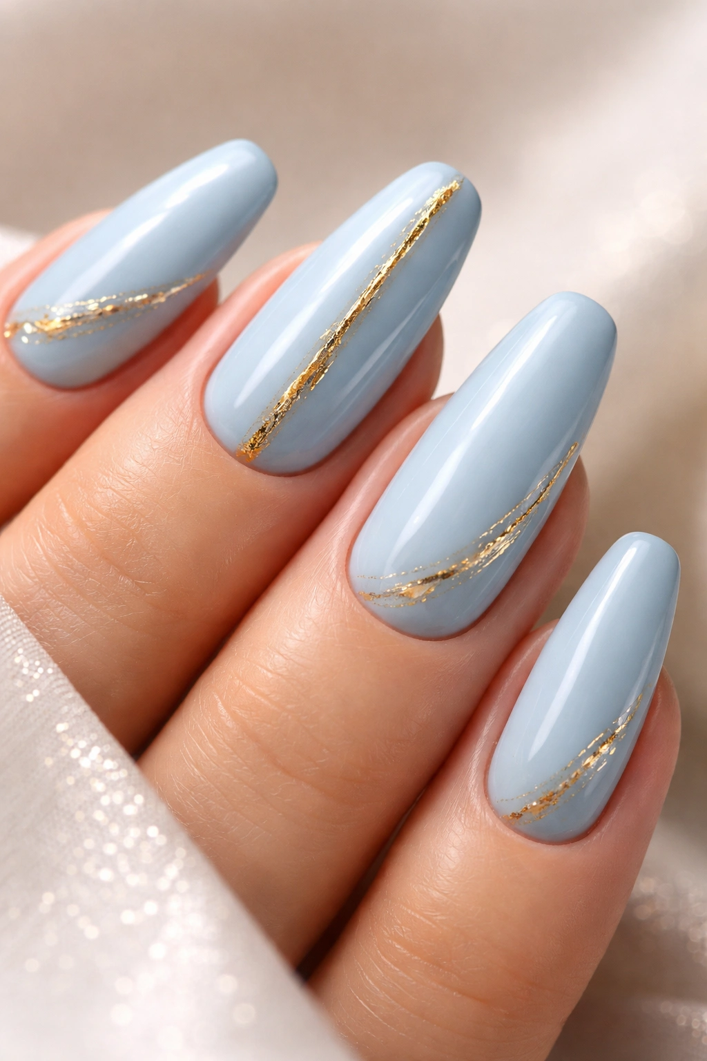 Close-up of light blue nails with metallic gold accents
