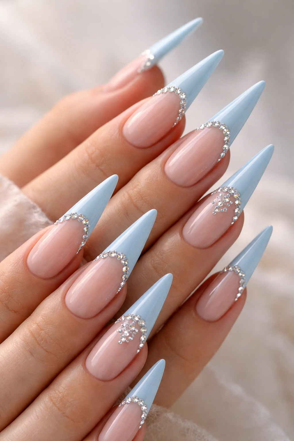 Close-up of baby blue French tip nails with rhinestone accents along the tips