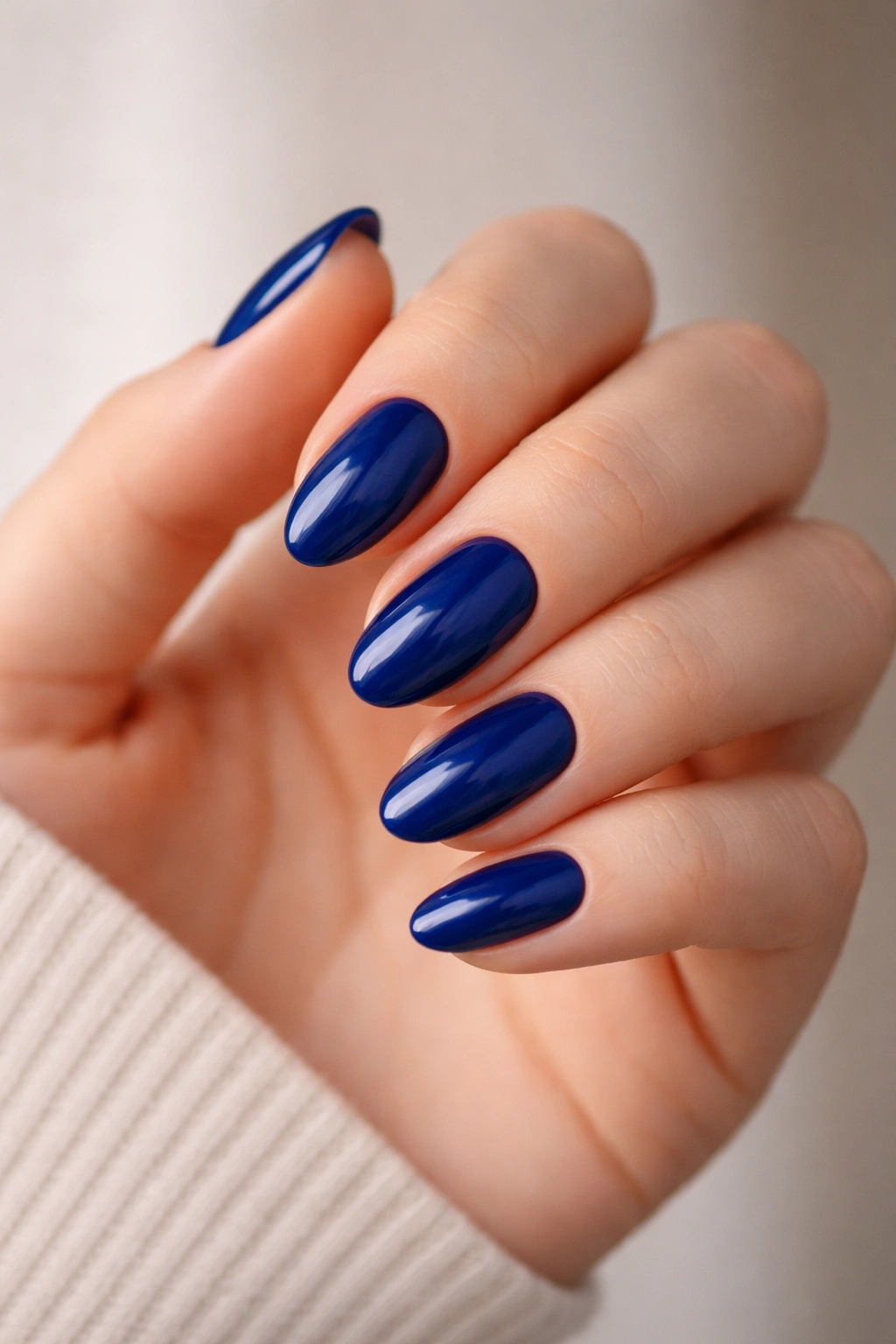 Close-up of short almond nails painted in deep blue, no design