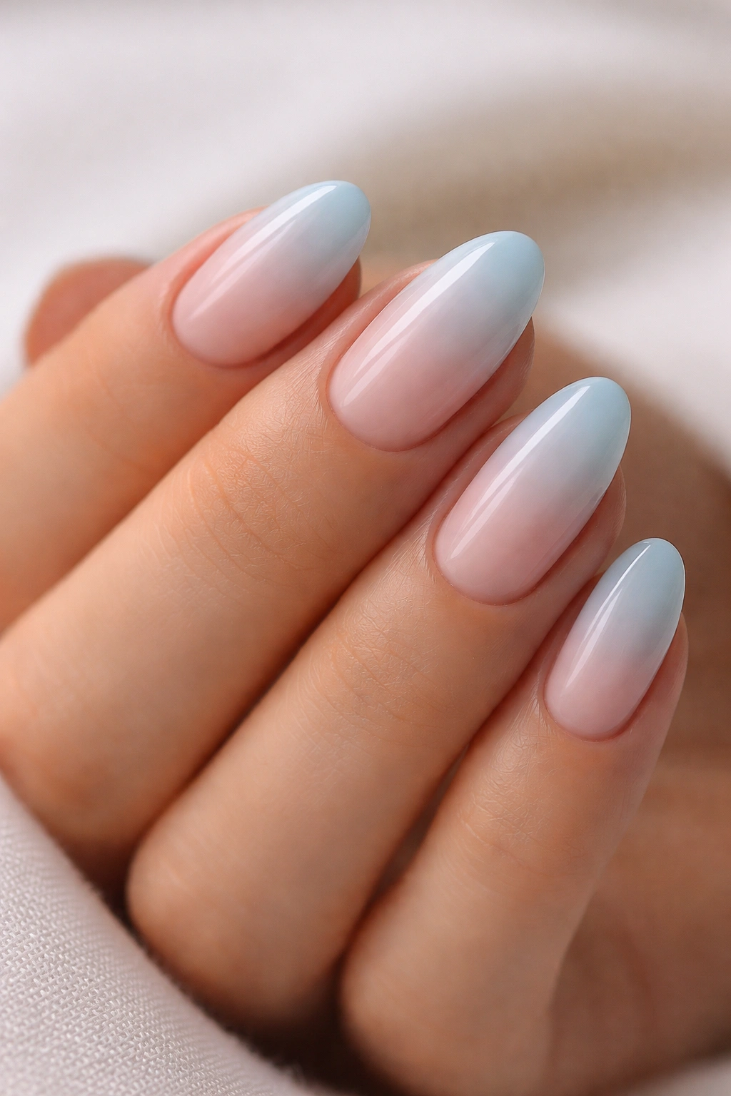 Close-up of light blue ombré almond nails on short nails with nude-to-blue gradient
