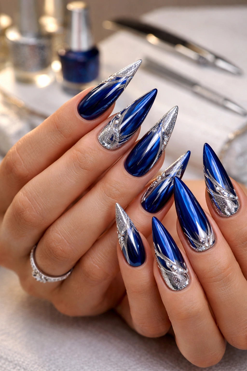 Close-up of blue and silver stiletto nails with smooth base and silver accents