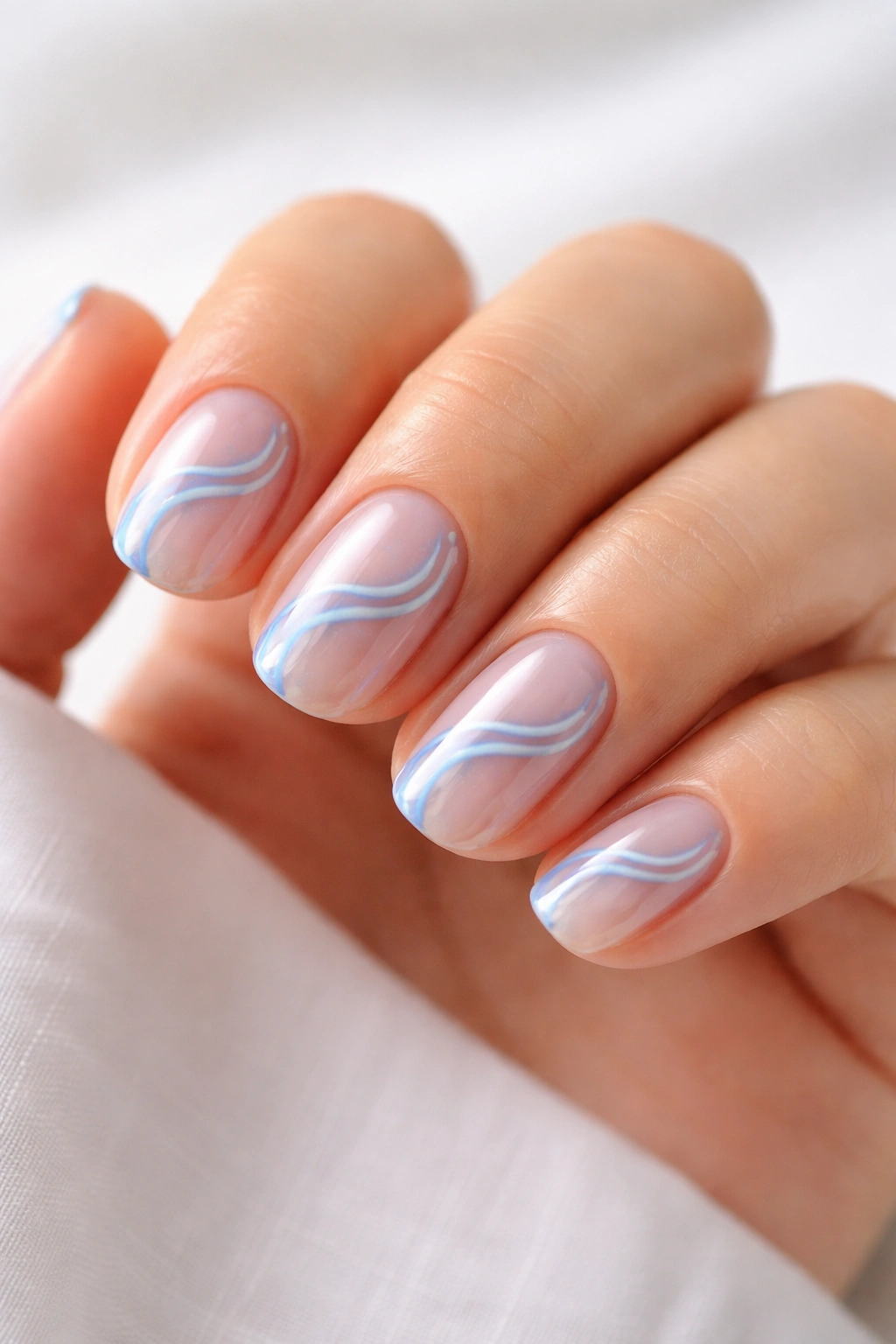 Close-up of blue swirls on clear short oval nails with negative space