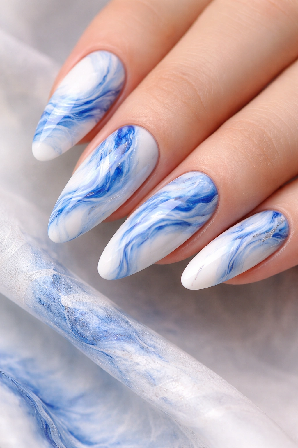 Close-up of blue and white marble nail design with veined swirls