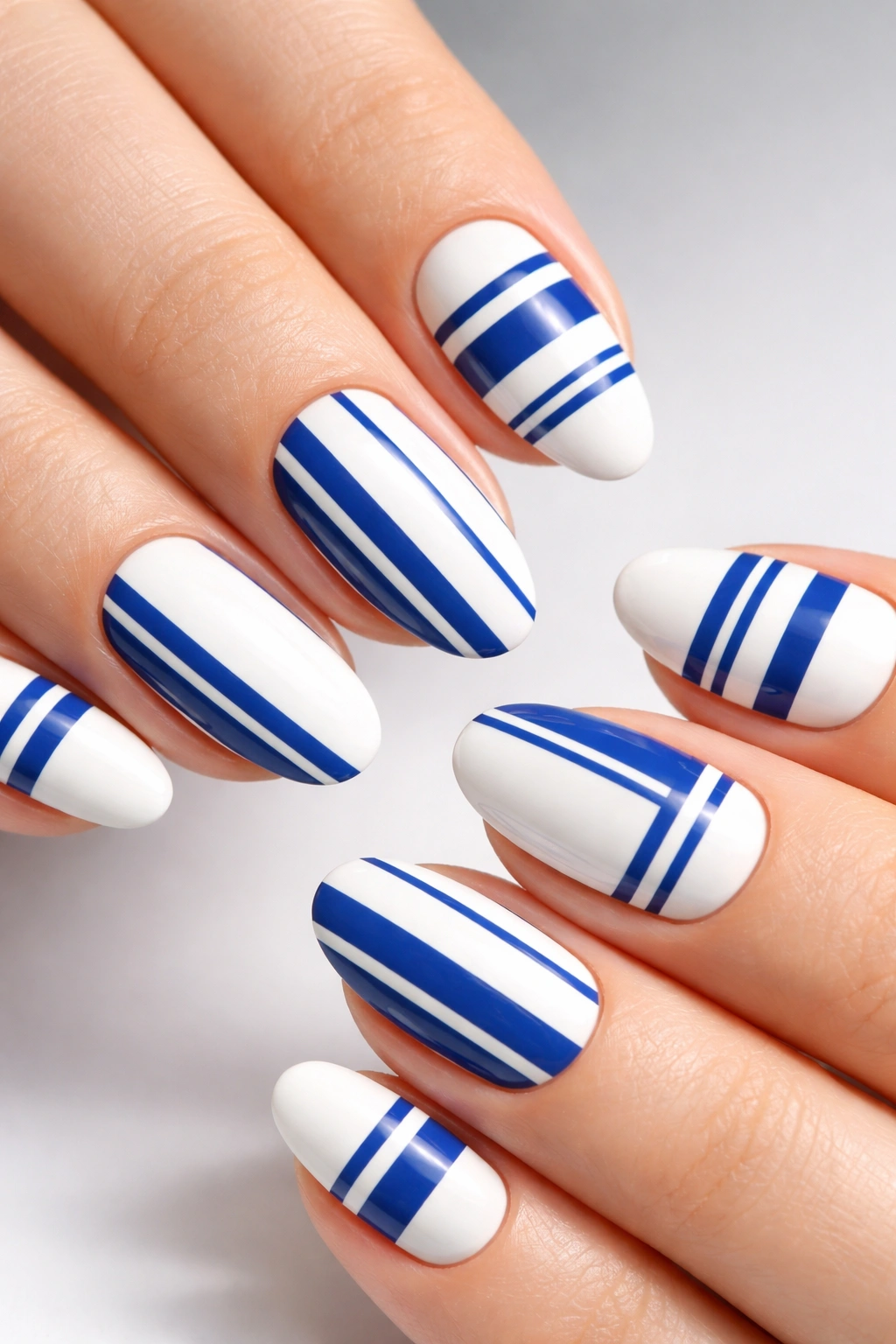 Close-up of white nails with crisp blue geometric striped patterns
