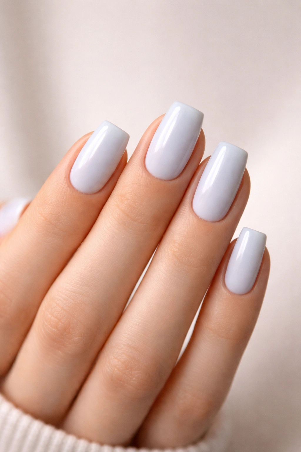 Soft square blueberry milk nails on a hand with a neutral backdrop