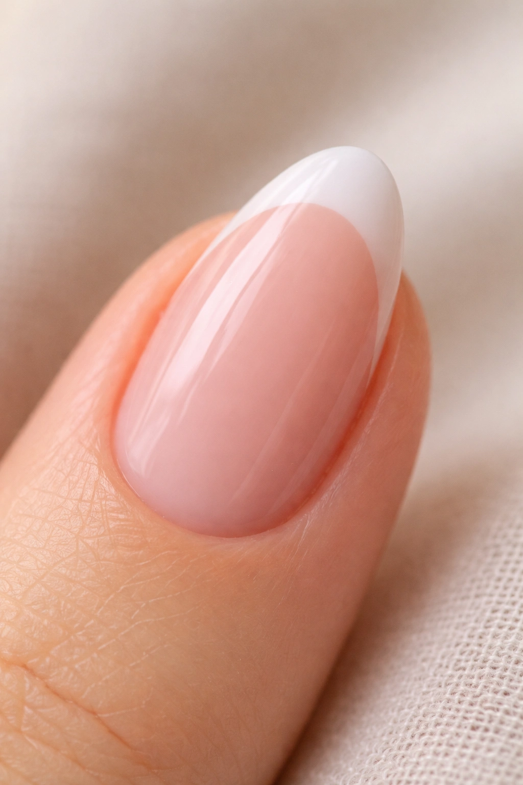 Close-up of a short almond nail with translucent pink blush base and white tip.