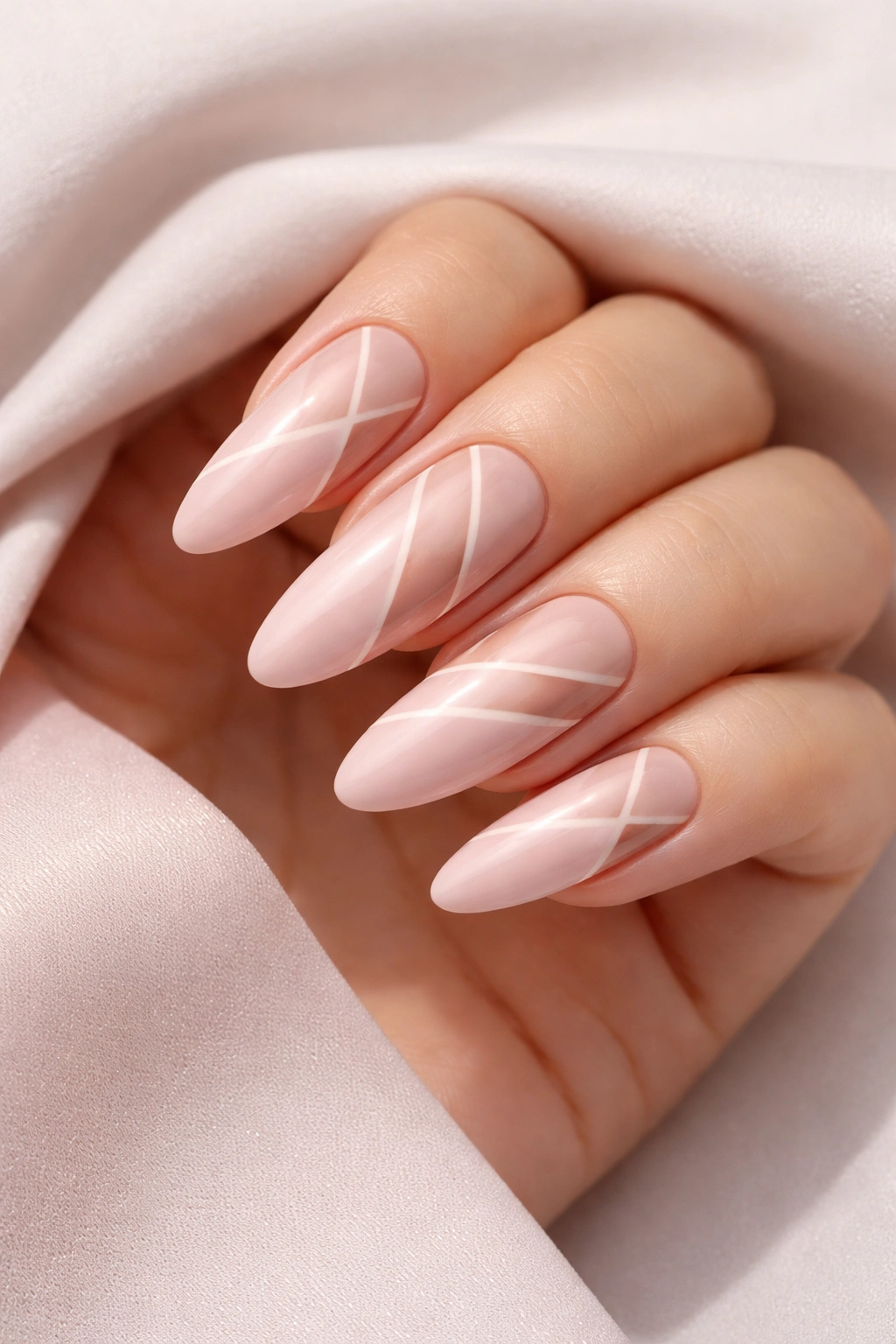 Close-up of blush pink nails with negative-space geometric art on long ovals