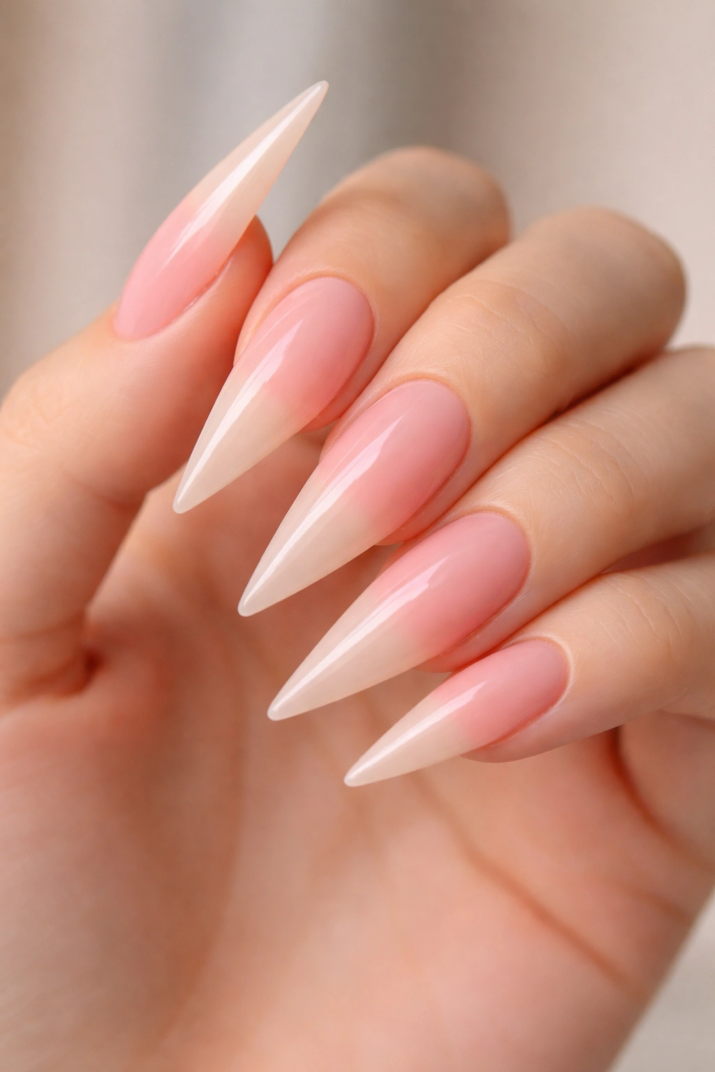 Close-up of blush pink to nude ombre stiletto nails with glossy finish