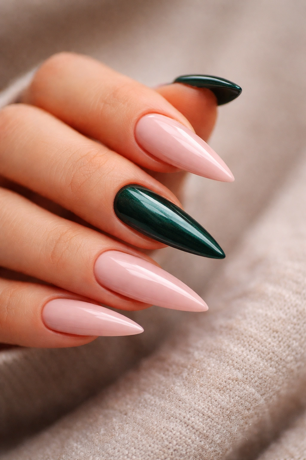 Close-up of blush pink nails with emerald green accent nail