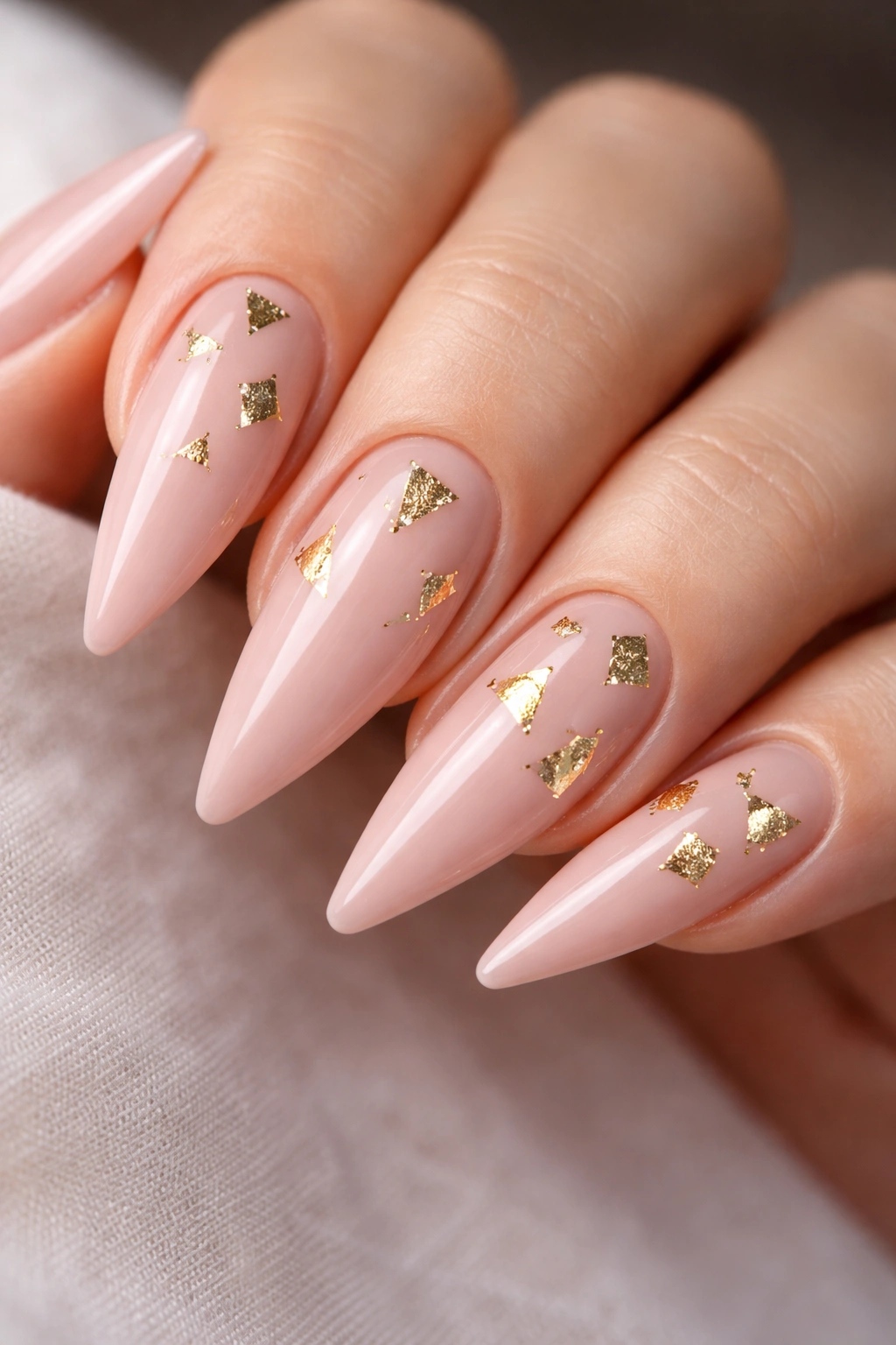 Close-up of blush pink nails with tiny geometric gold negative space