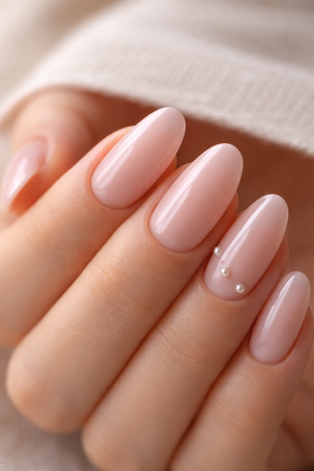 Close-up of blush pink nails with tiny pearl accents