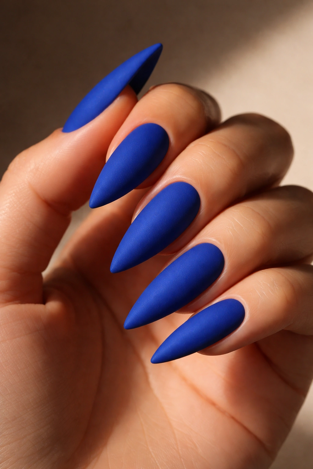 Bold cobalt blue matte stiletto nail close-up on a hand