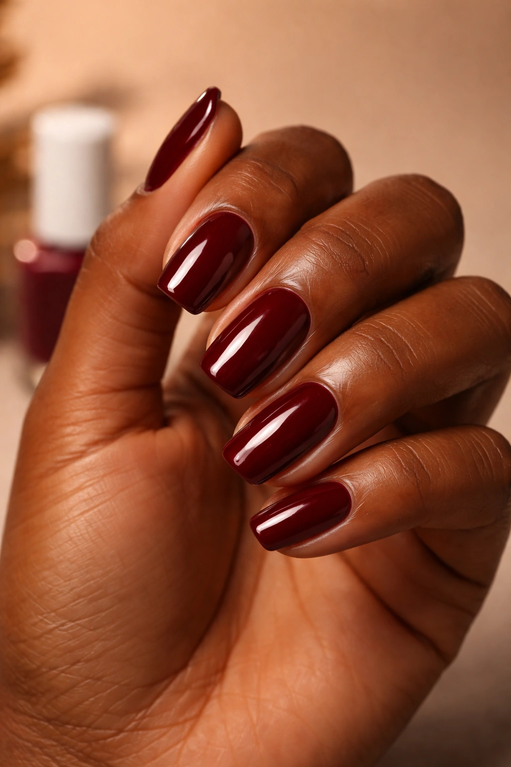 Close-up of deep skin tone hand with Bordeaux wine red nails