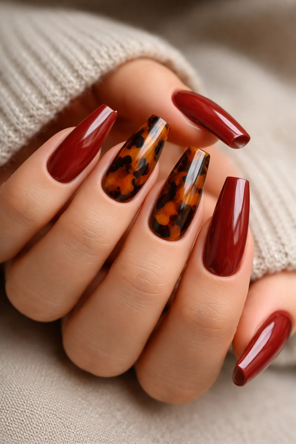 Nails showing brick red and tortoiseshell accents on a ballerina manicure.