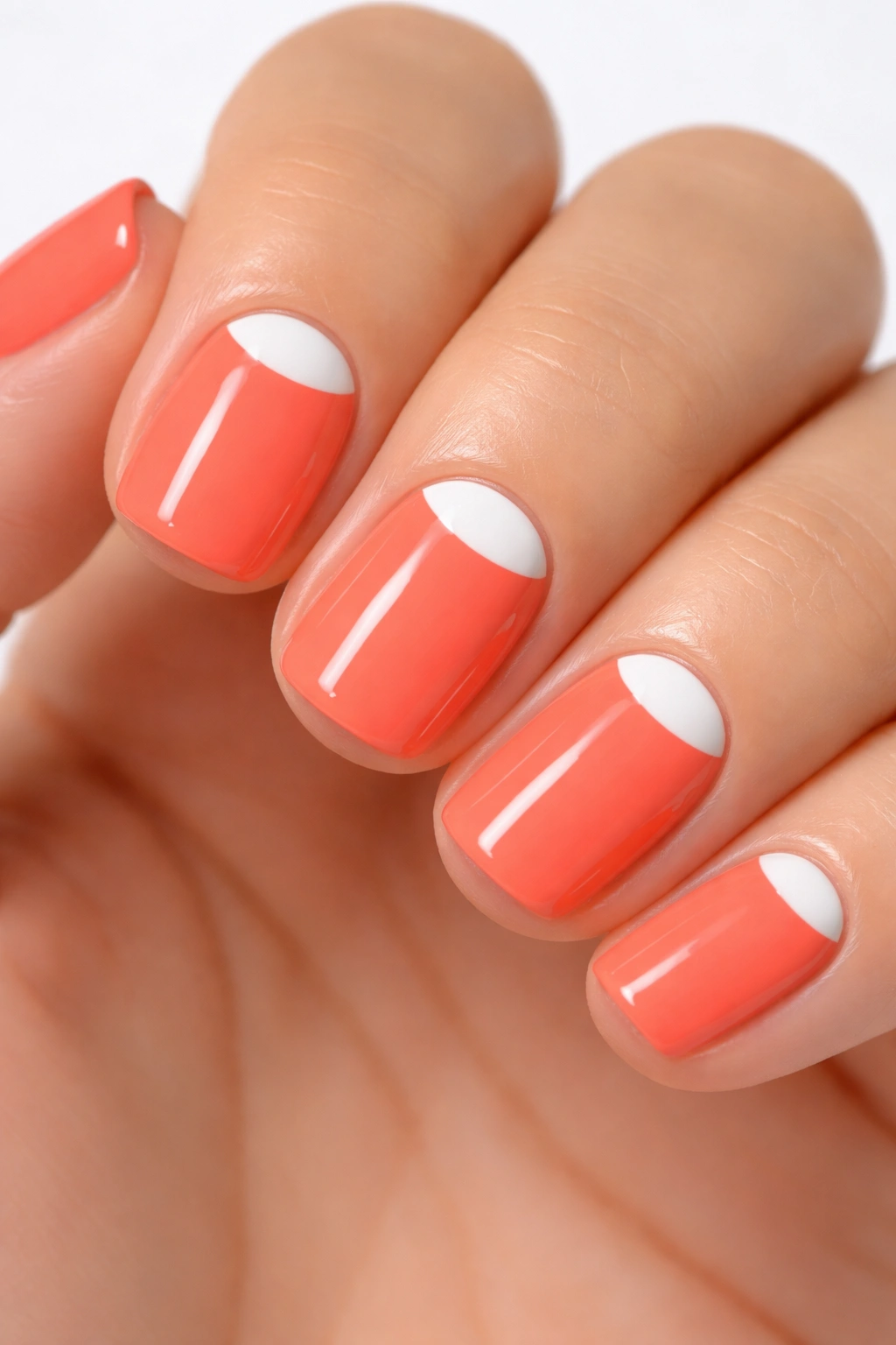 Bright coral nails with white half-moon lunula on short squoval nails