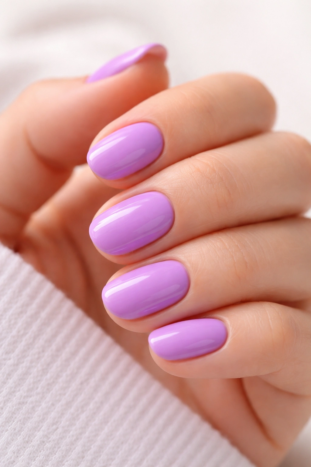 Close-up of short oval nails in bright lilac with vibrant finish