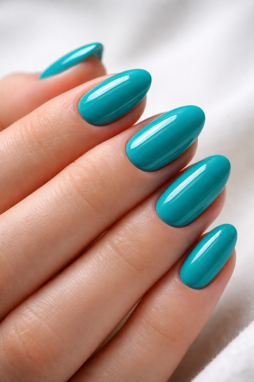 Close-up of bright teal short almond nails with a crisp glossy finish