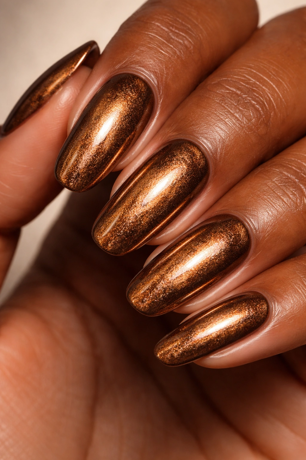 Close-up of nails with bronze metallic polish reflecting light
