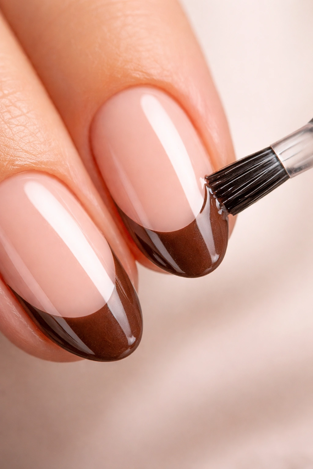 Close-up of edge sealing on brown French tips with topcoat.