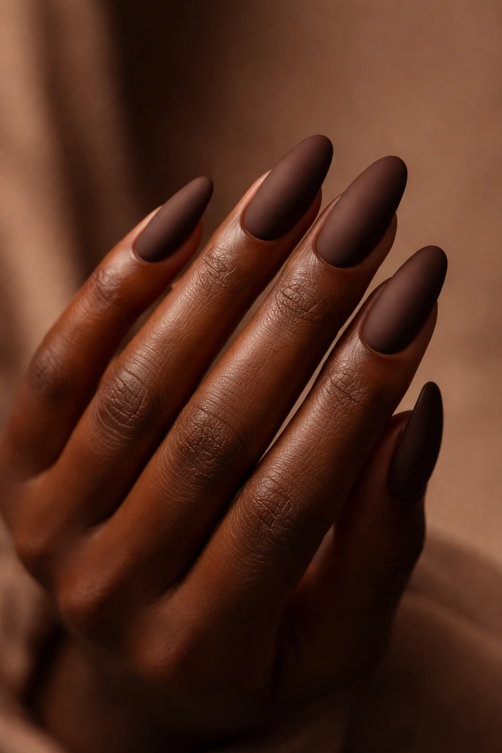 Close-up of a dark-skinned hand with chocolate brown matte nails.