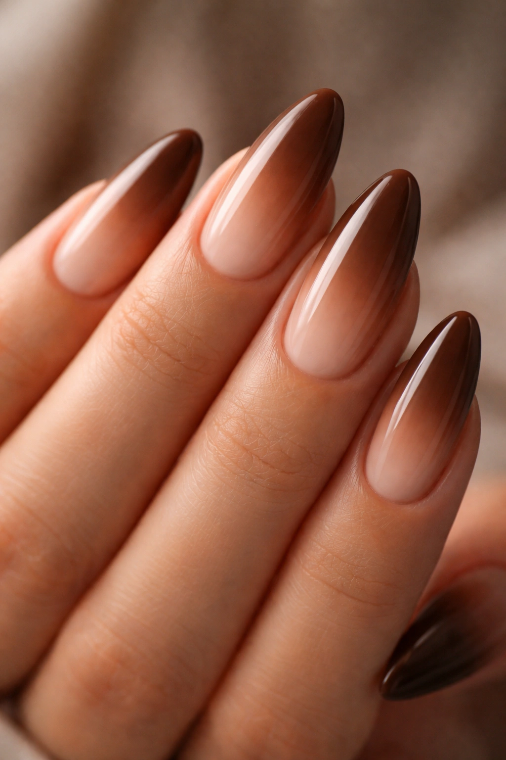Close-up brown to nude ombre almond nails with subtle fade