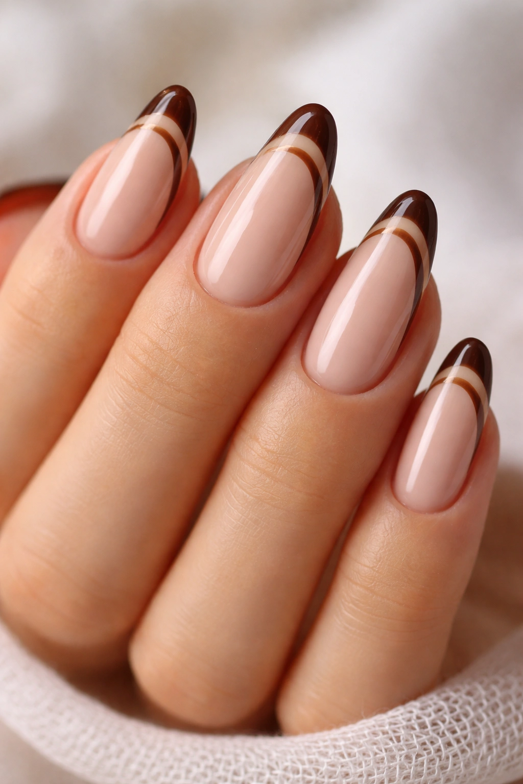 Close-up brown swirled French almond nails with sheer base