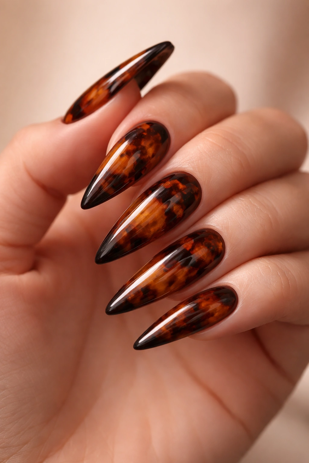 Close-up of brown tortoiseshell stiletto nails on a hand.