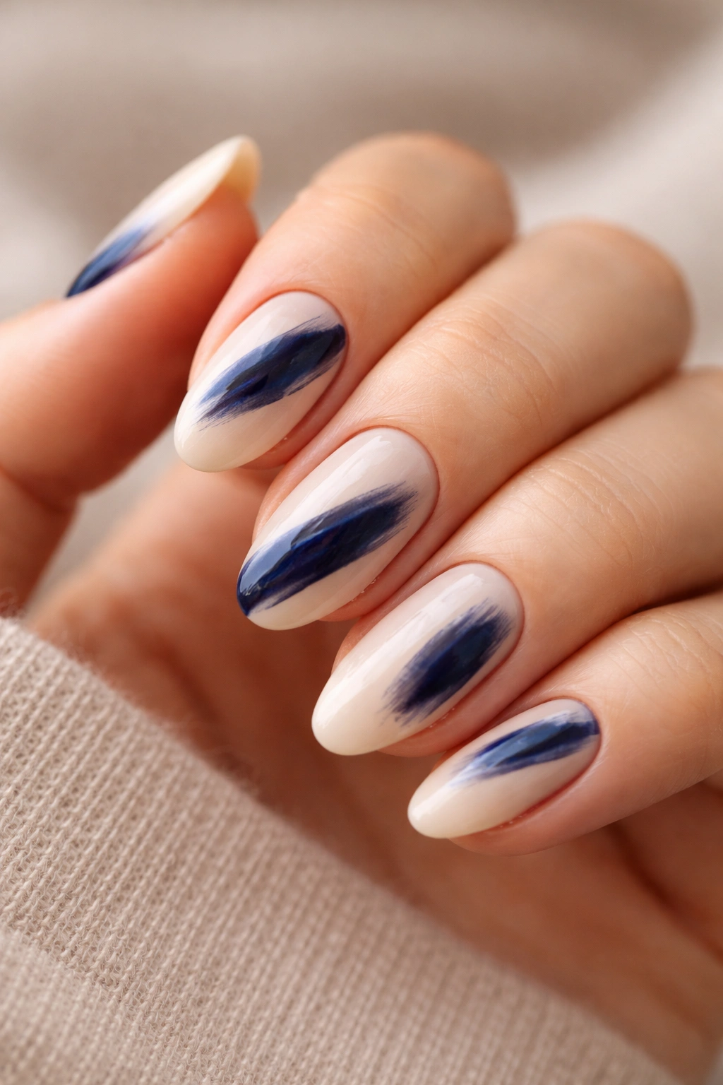 Close-up of short almond nails with bold painterly brush stroke on nude base