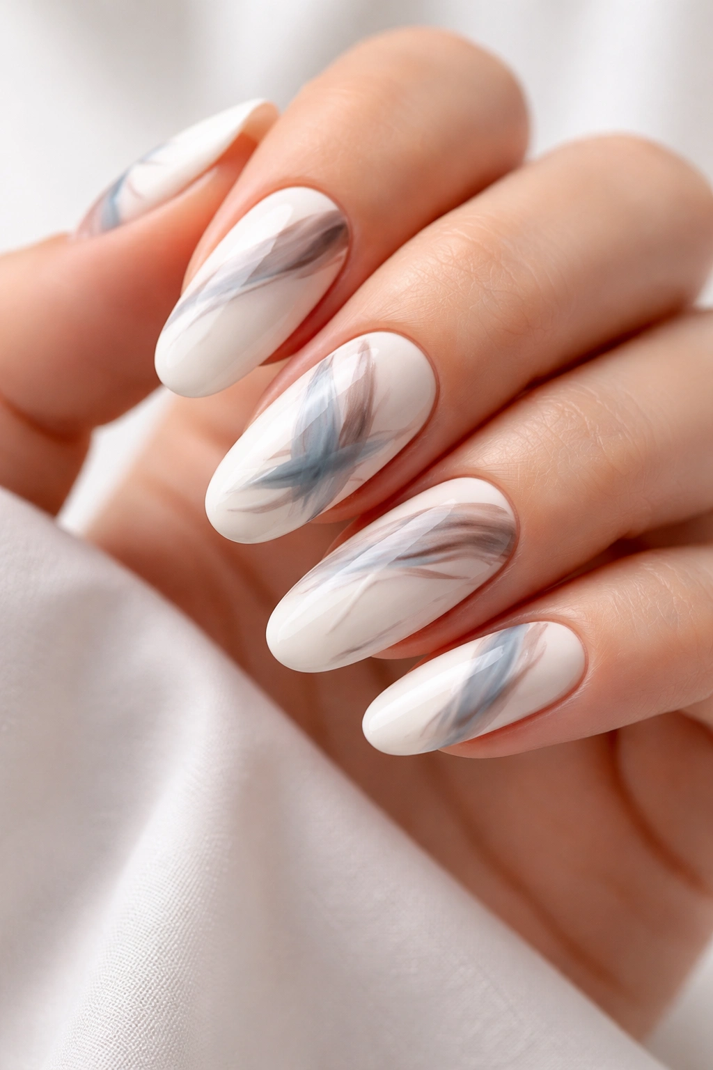 Close-up of white nails with abstract brushstroke art in taupe and blue