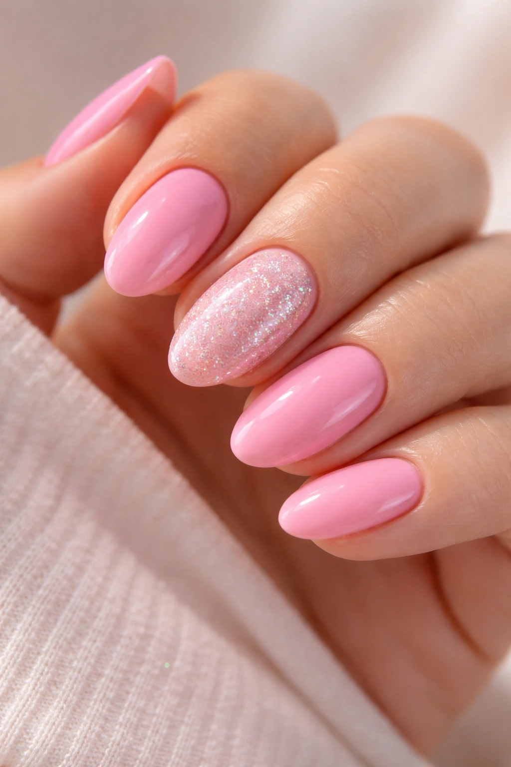 Close-up of bubblegum pink nails with glitter accents on selected nails.
