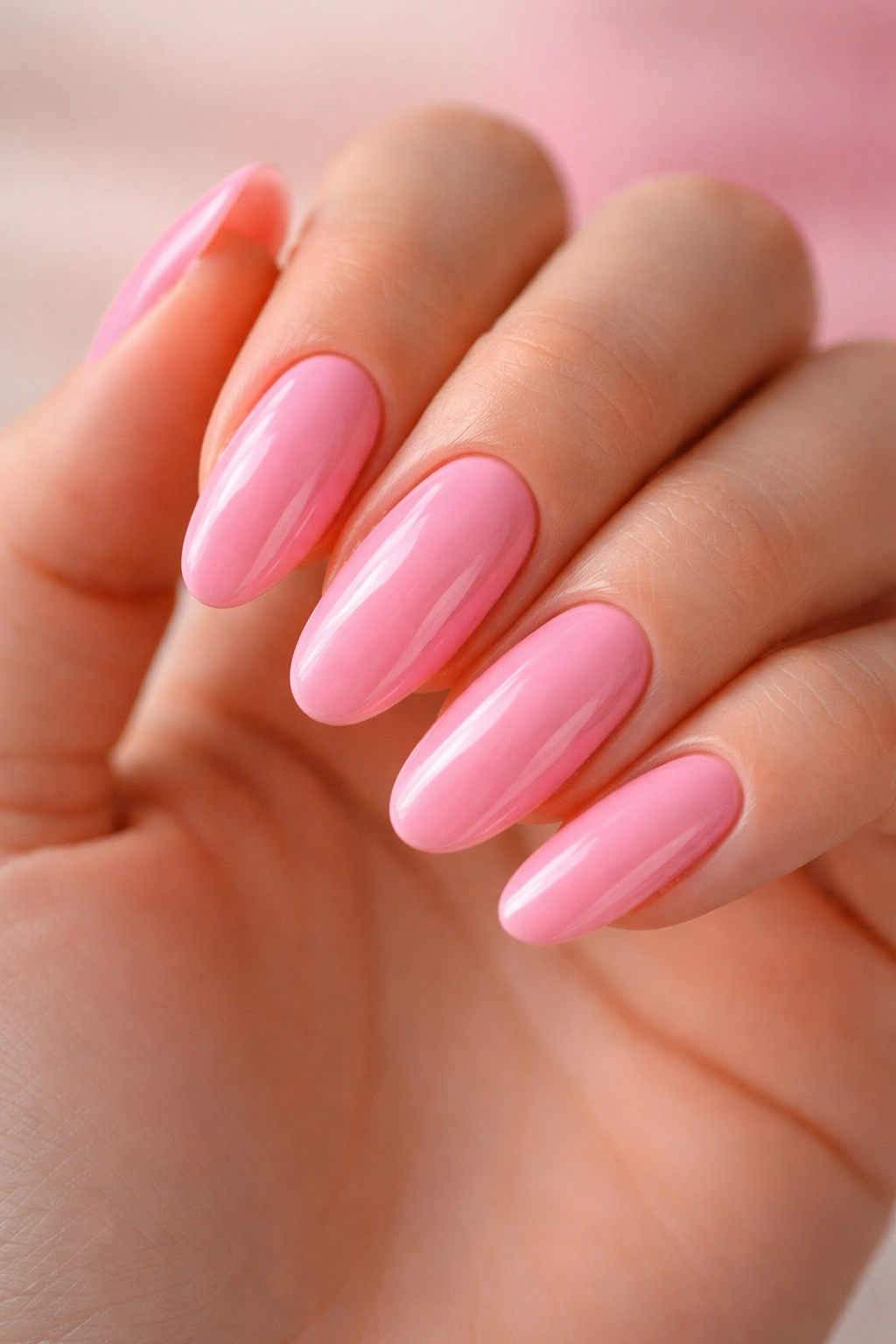 Close-up of long oval bubblegum pink nails with high-gloss finish