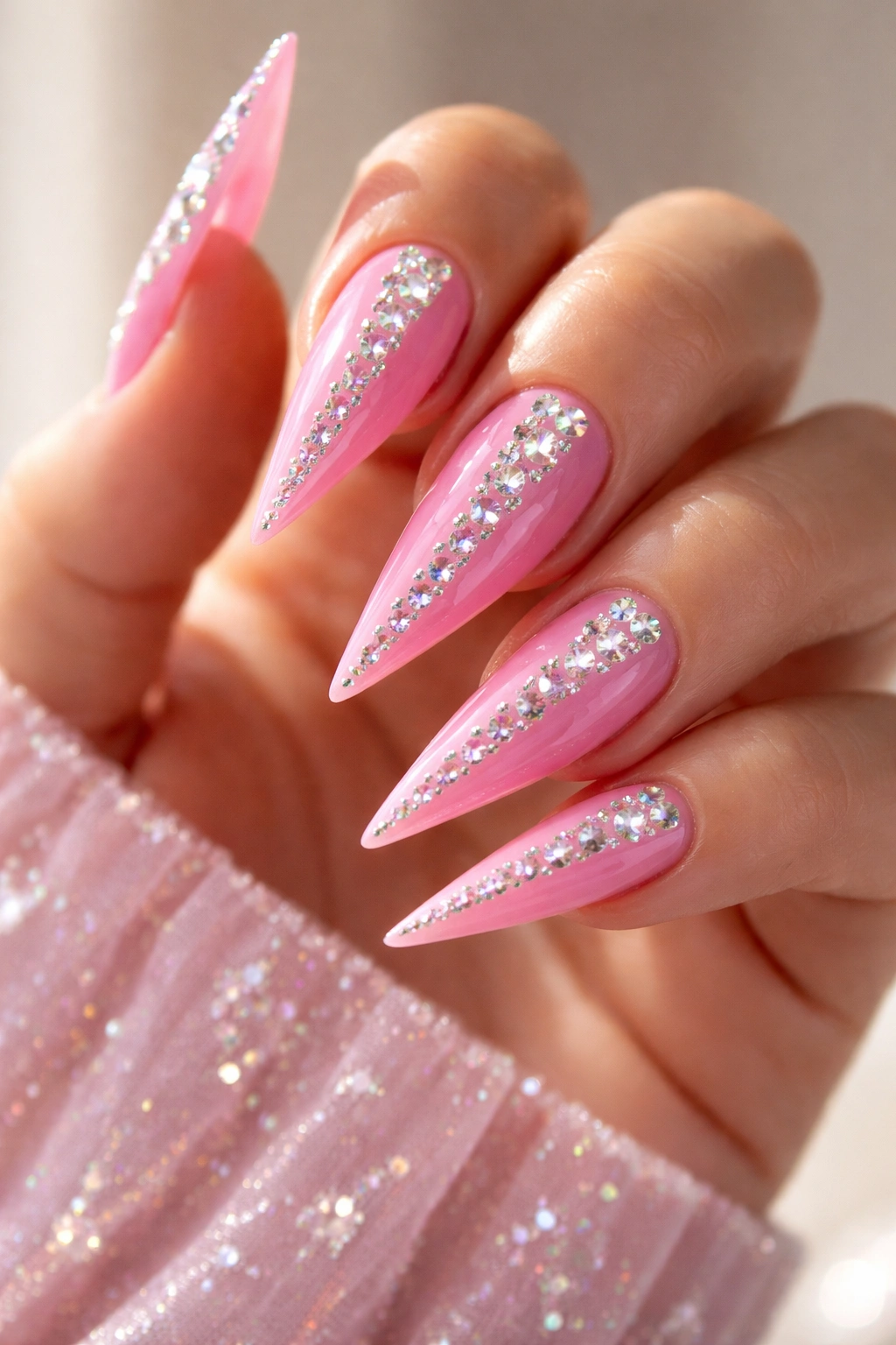 Bubblegum pink stiletto nails with rhinestones along tips