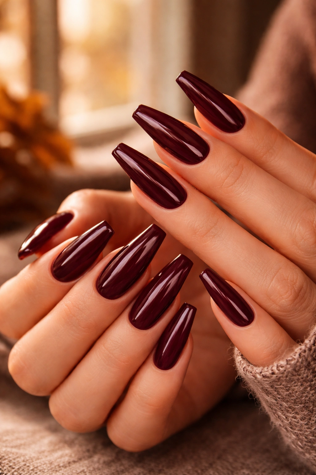 Close-up of deep burgundy acrylic nails with glossy finish