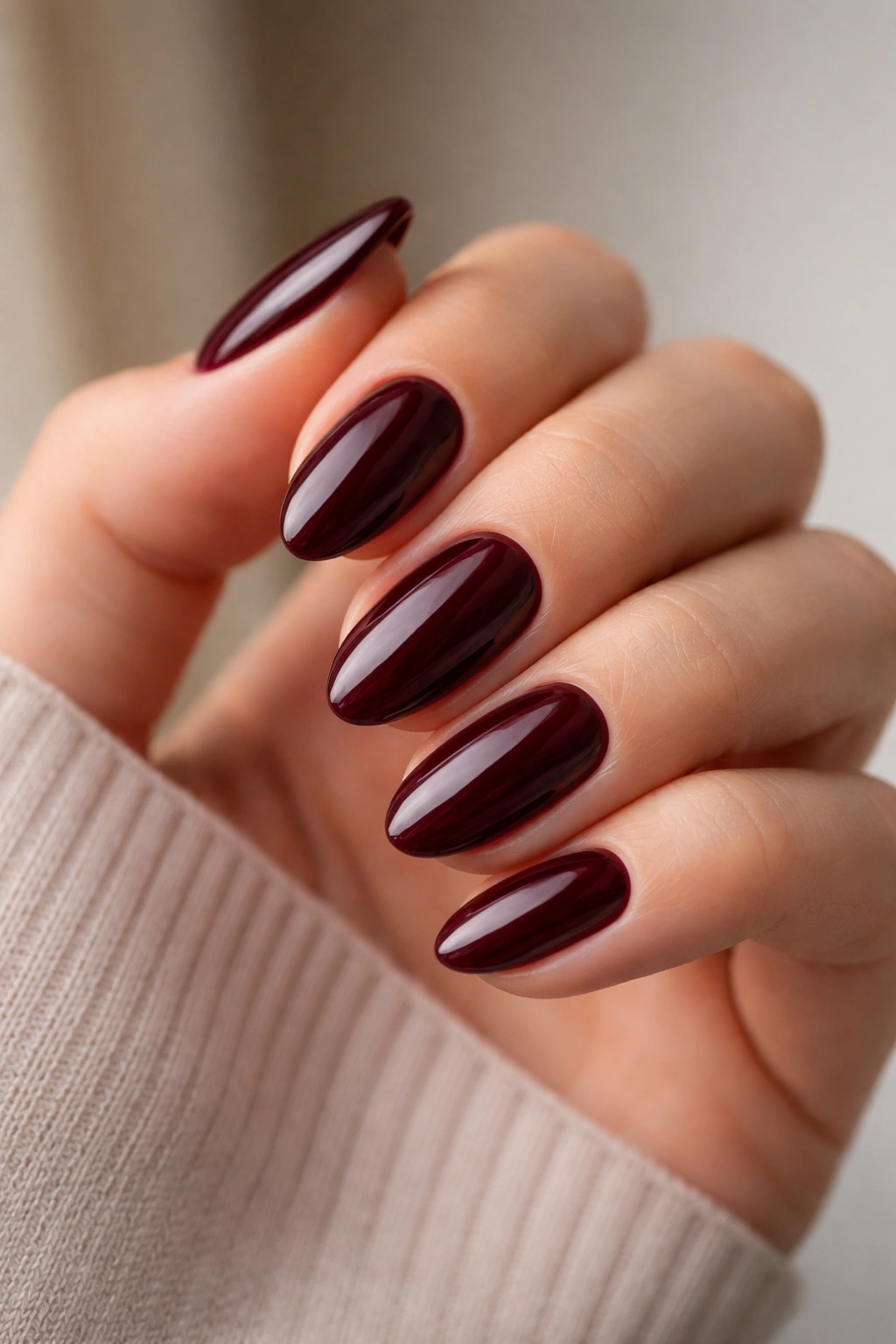 Close-up of short almond nails in burgundy glossy polish