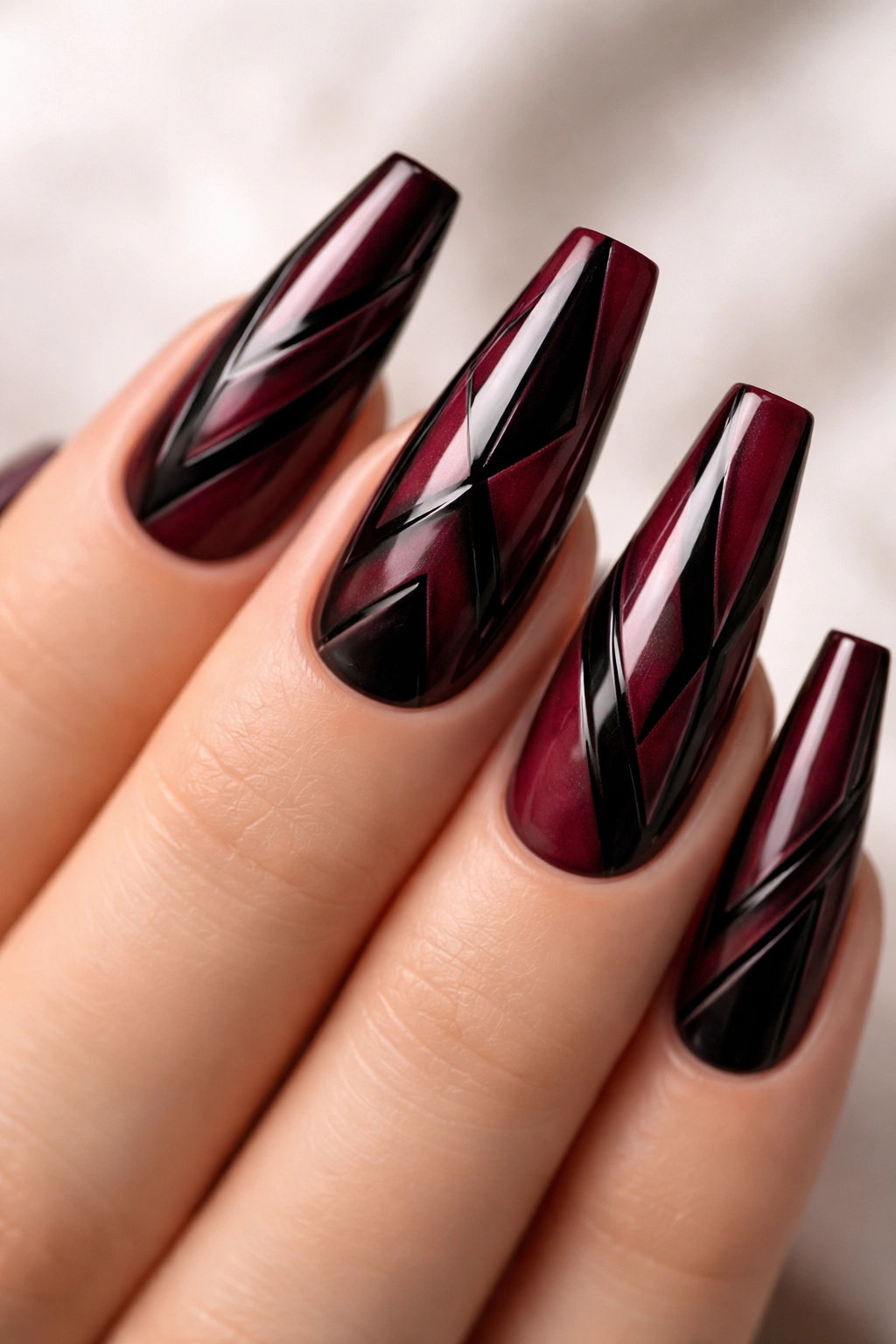 Nails with burgundy base and black geometric patterns