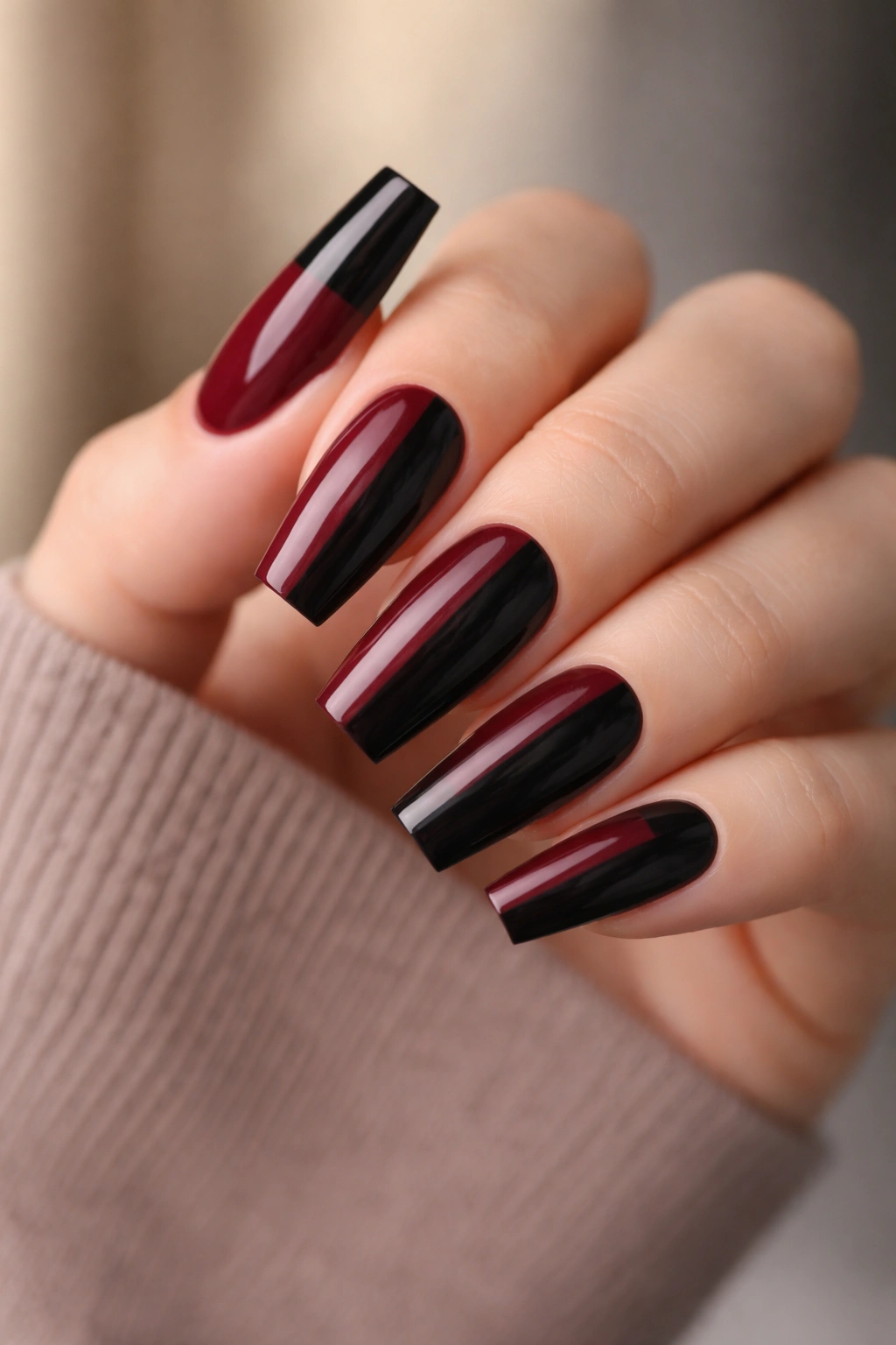 Close-up of medium coffin nails with burgundy and black vertical color block on a hand