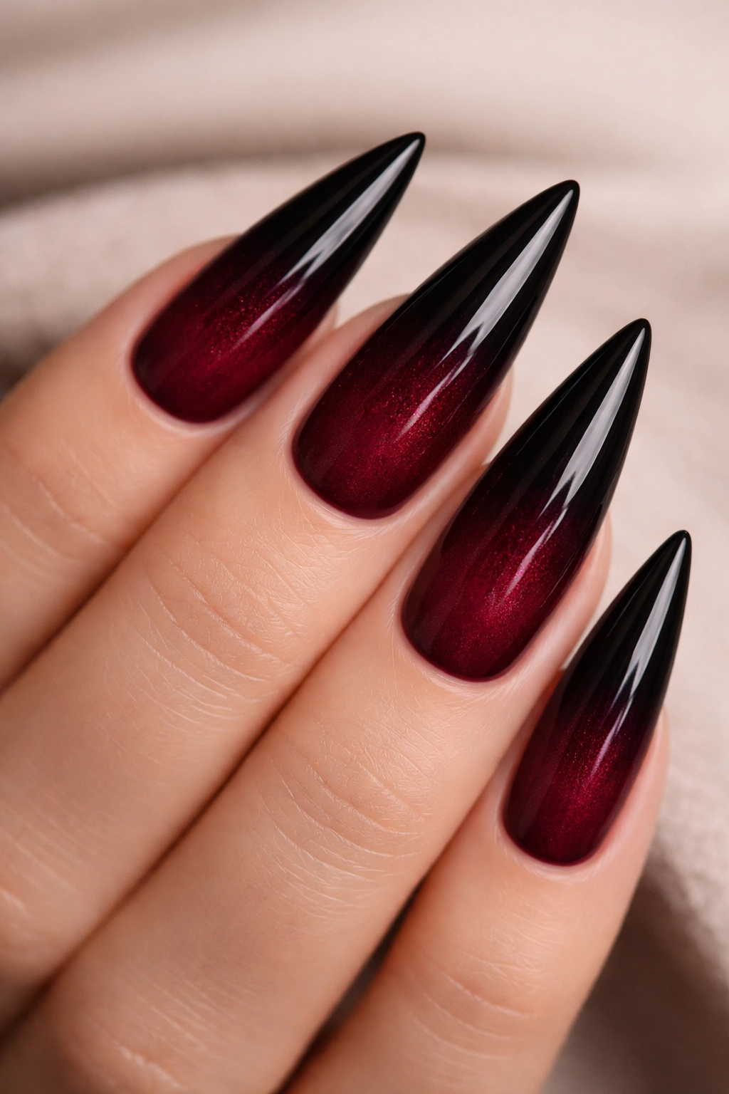 Close up of burgundy to black ombre stiletto nails with subtle shimmer