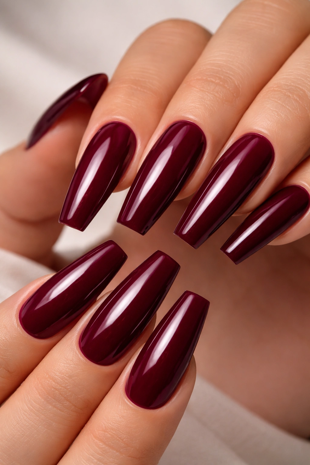 Close-up of tapered coffin nails in deep burgundy gradient.