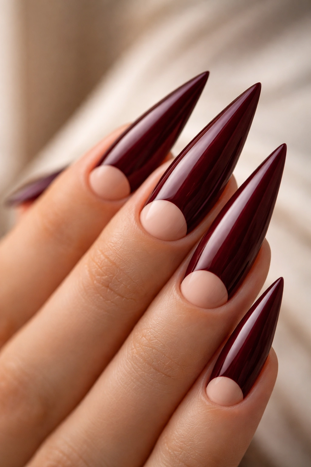 Burgundy curved stiletto nail with a base half-moon negative space