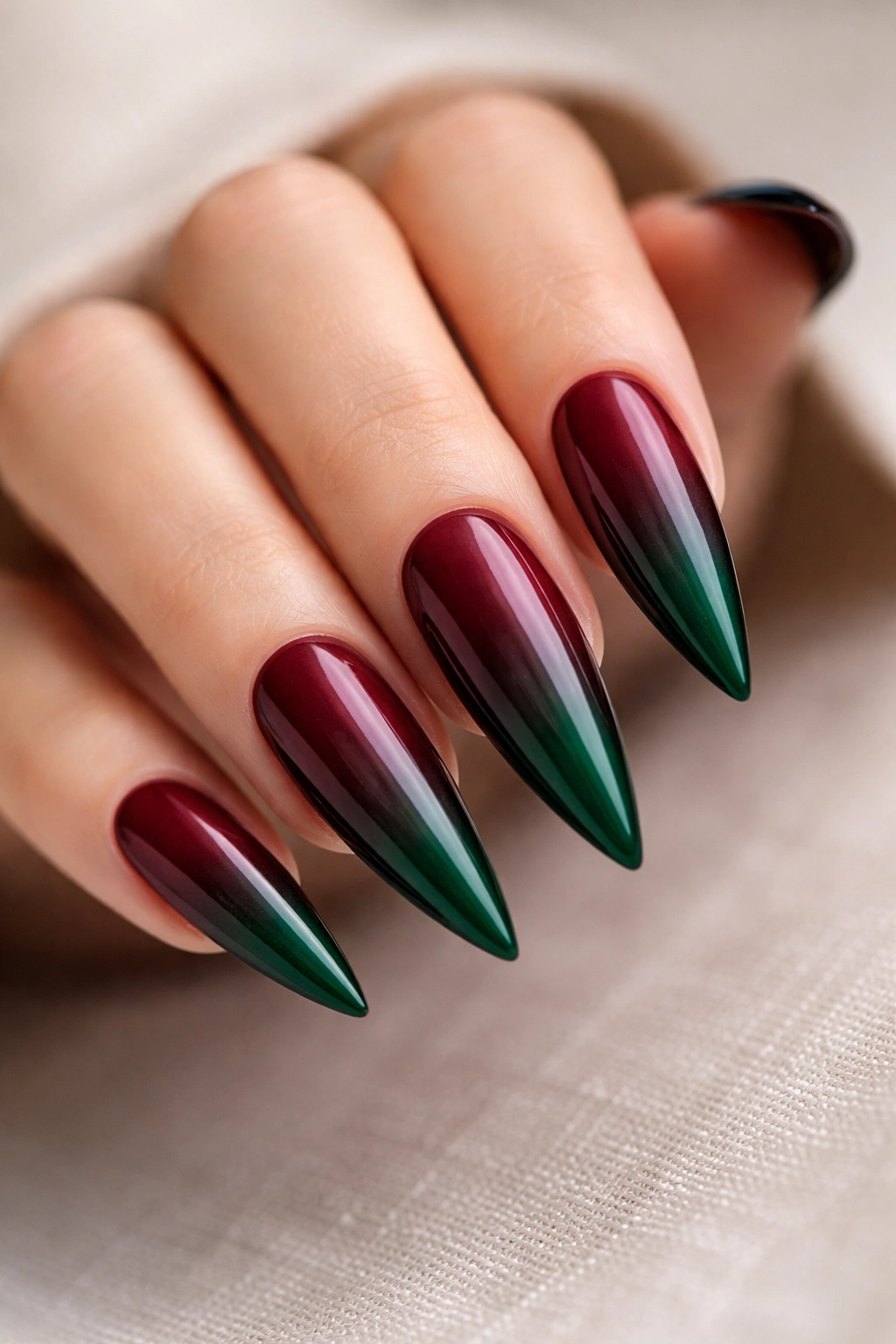 Close-up of burgundy to forest green gradient on stiletto nails
