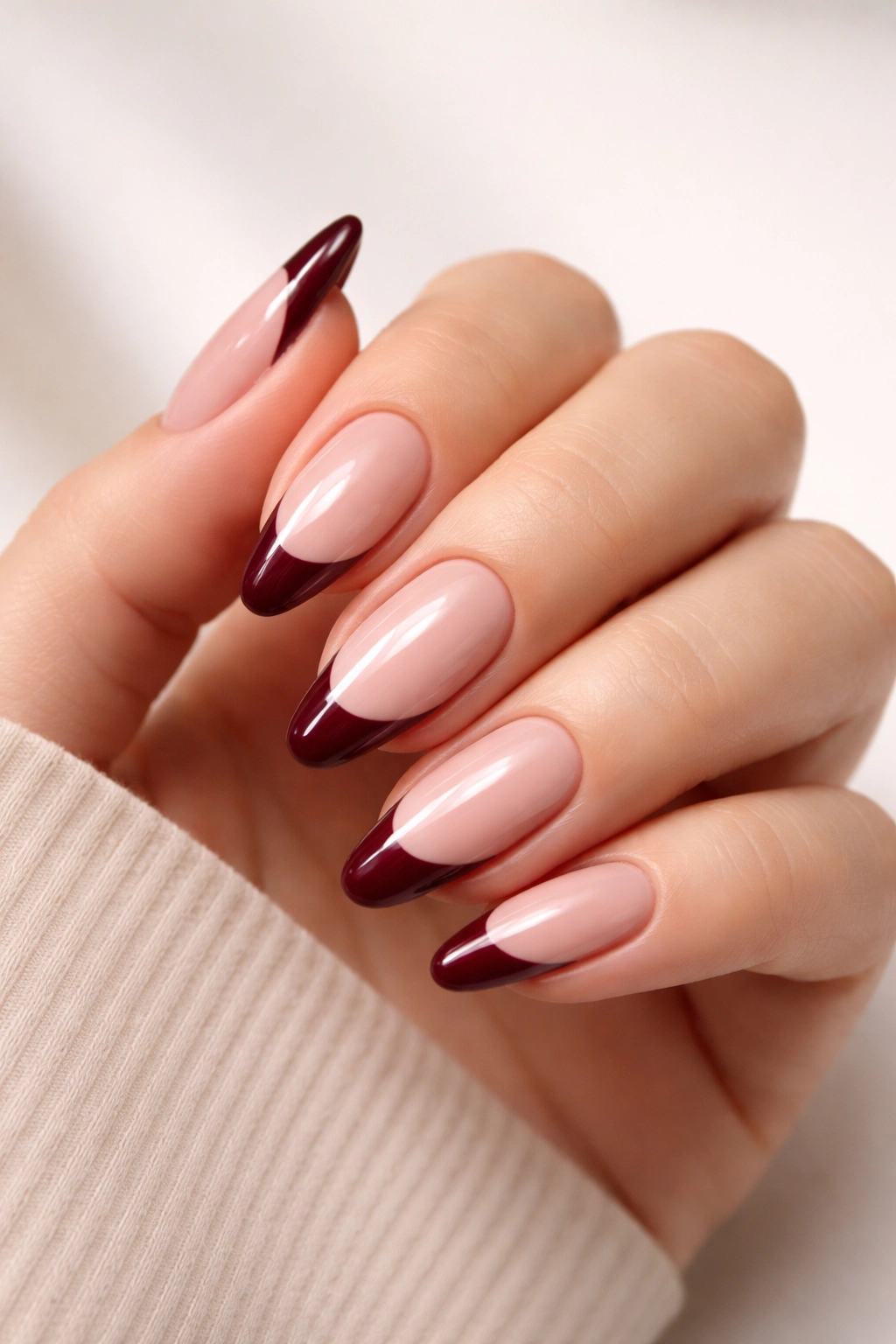 Close-up of burgundy French tips on a nude base nails with a curved burgundy tip