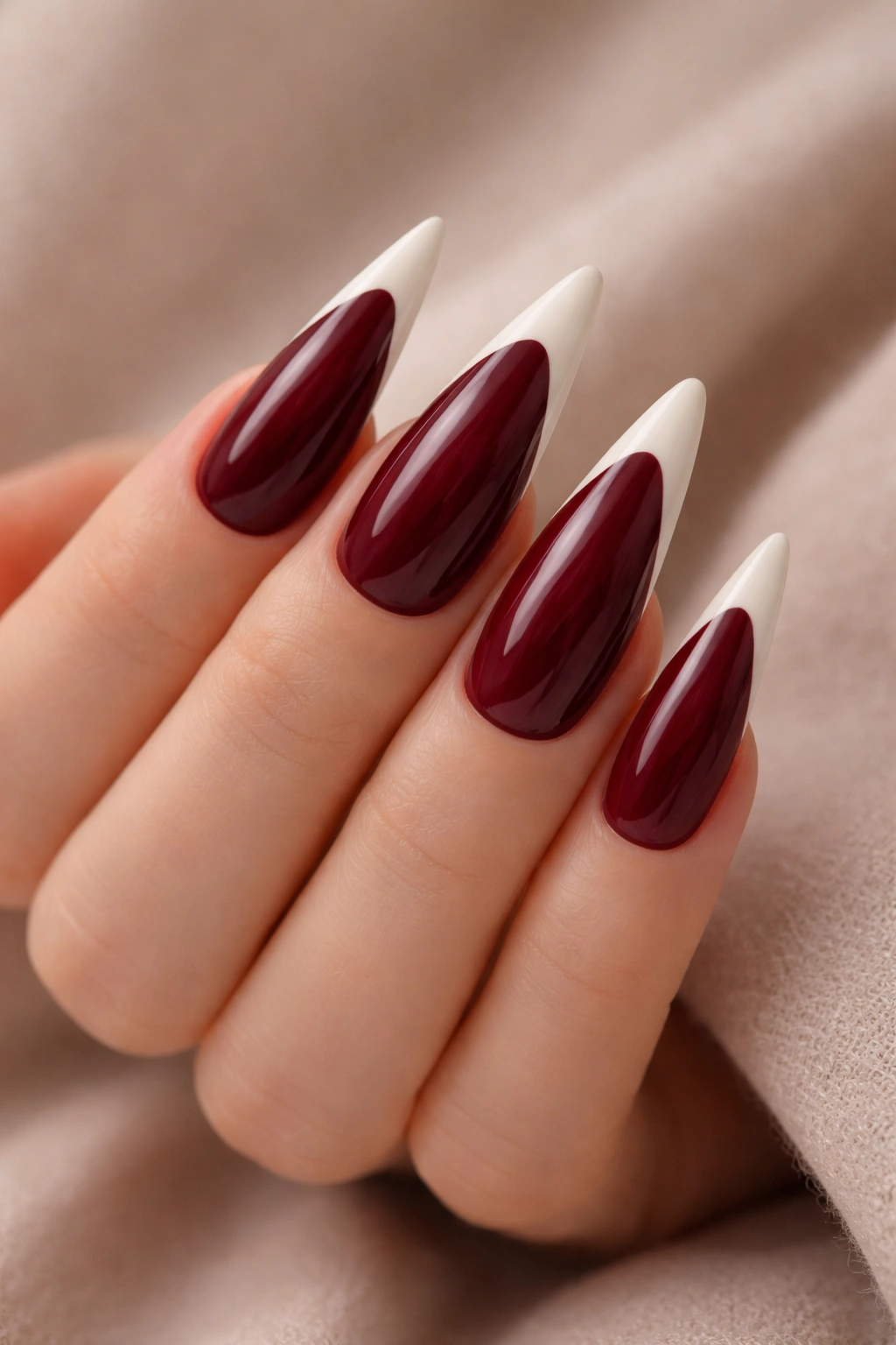 Close-up burgundy nails with white tips in stiletto shape