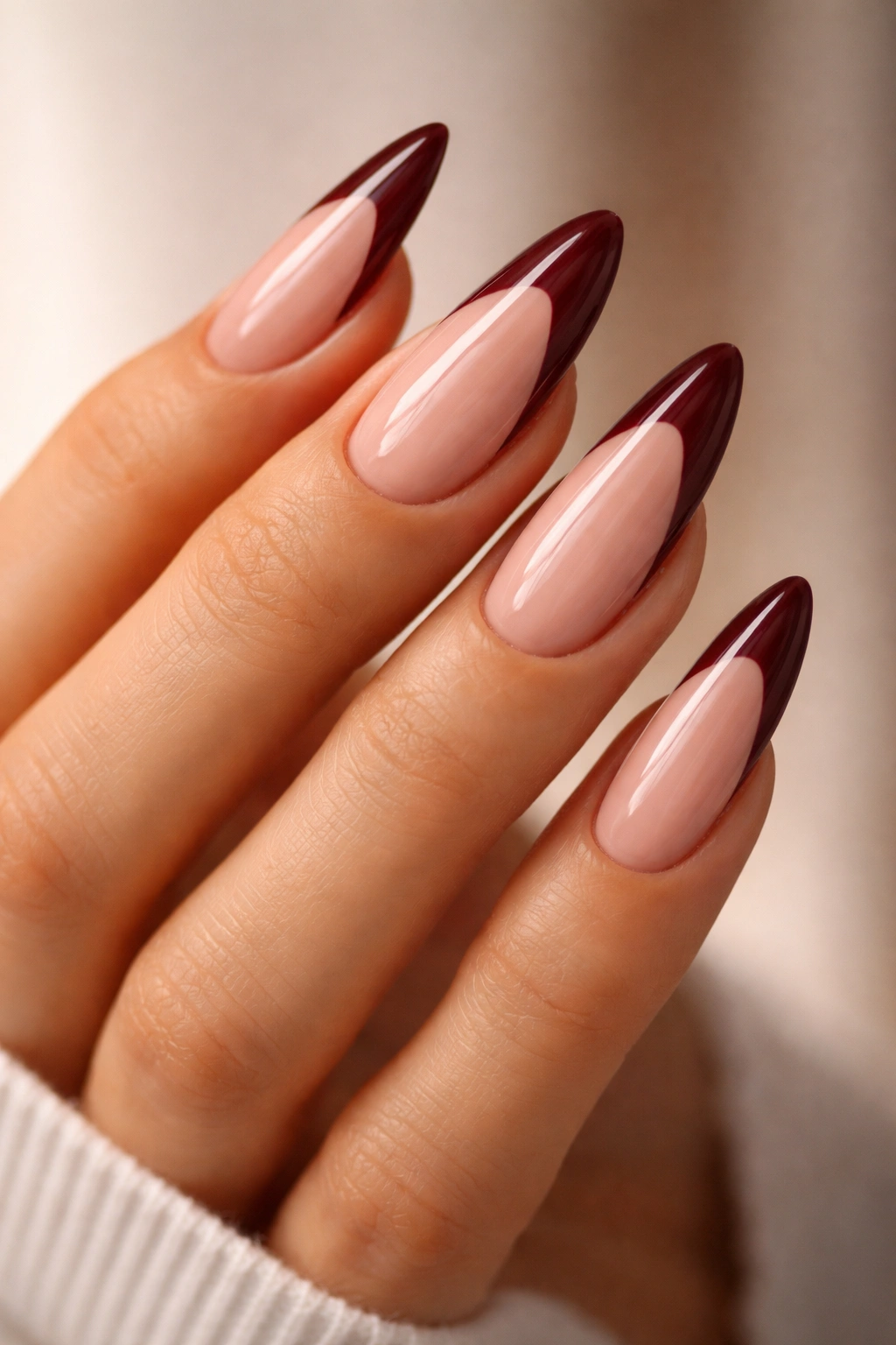 Long almond nails with burgundy French tips over a nude base