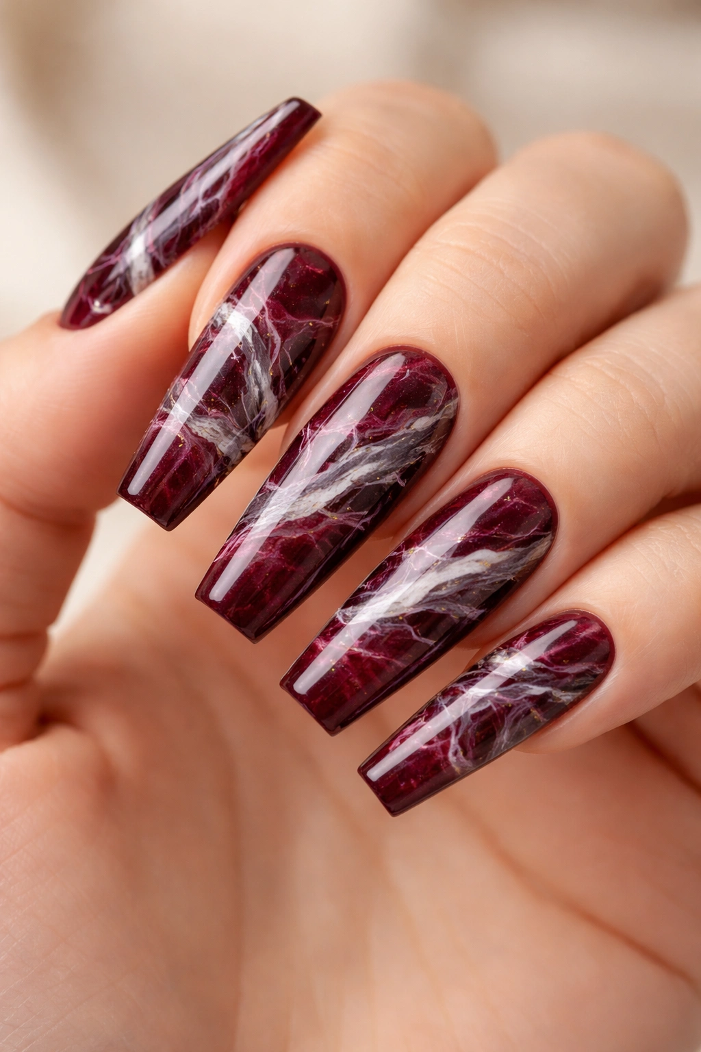 Close-up of burgundy coffin nails with marble veining