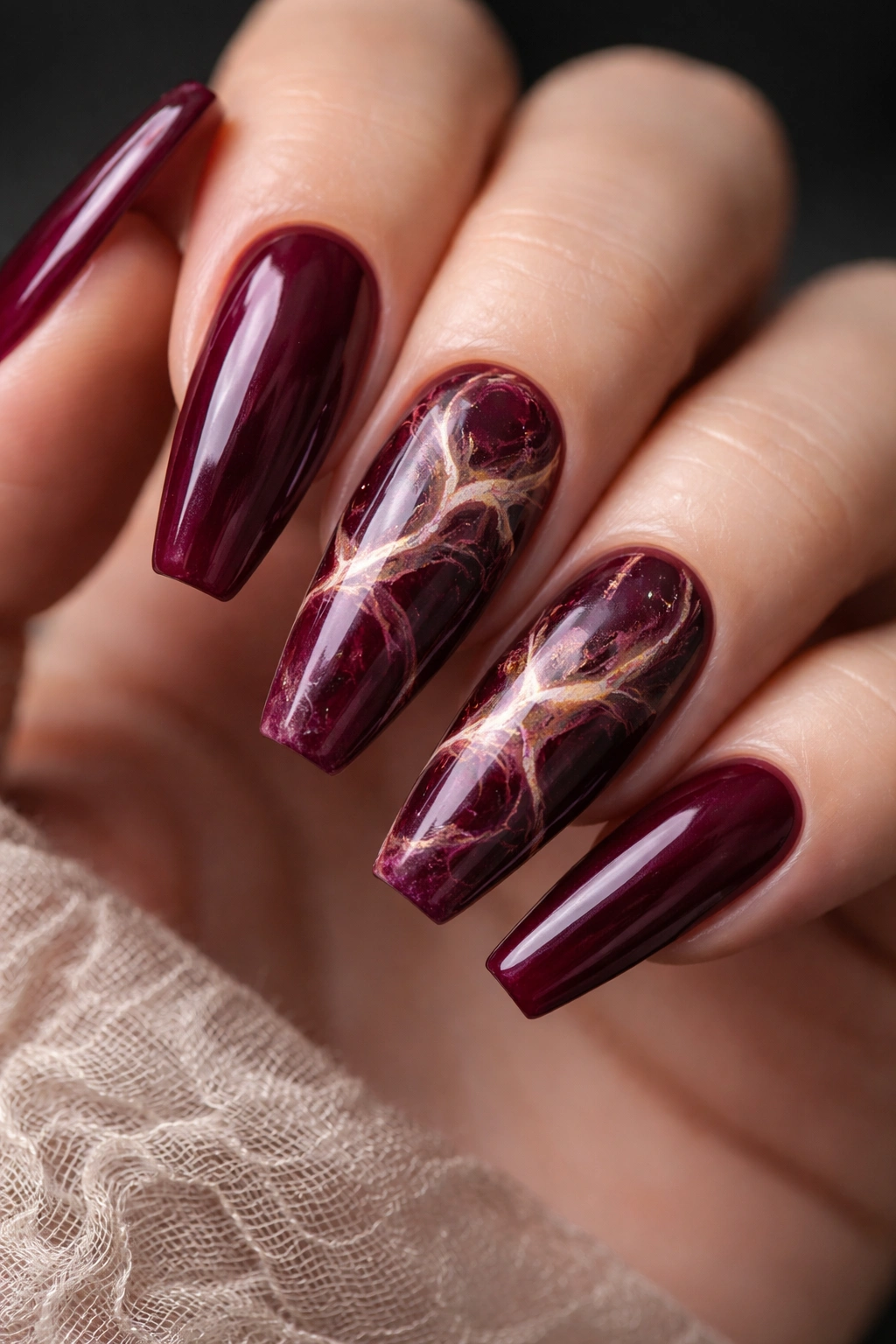 Nails featuring deep burgundy marble with cream and espresso veins